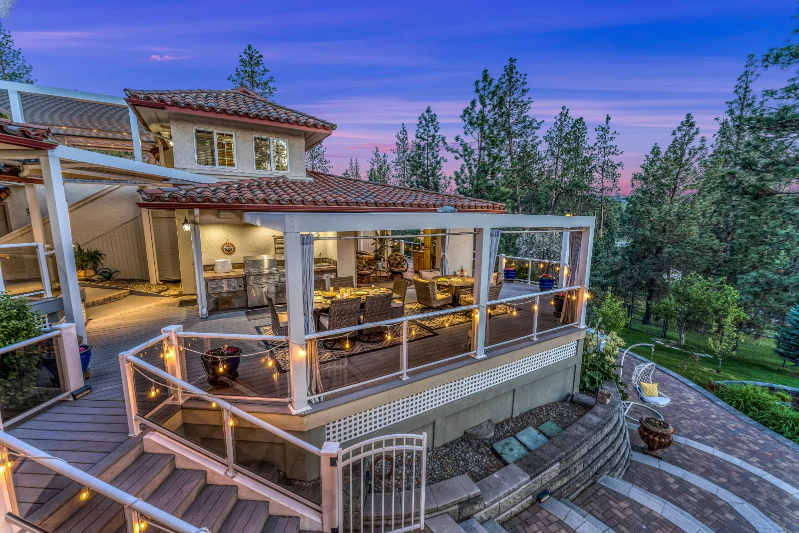 Elevated twilight view of the covered outdoor kitchen and dining deck among pines