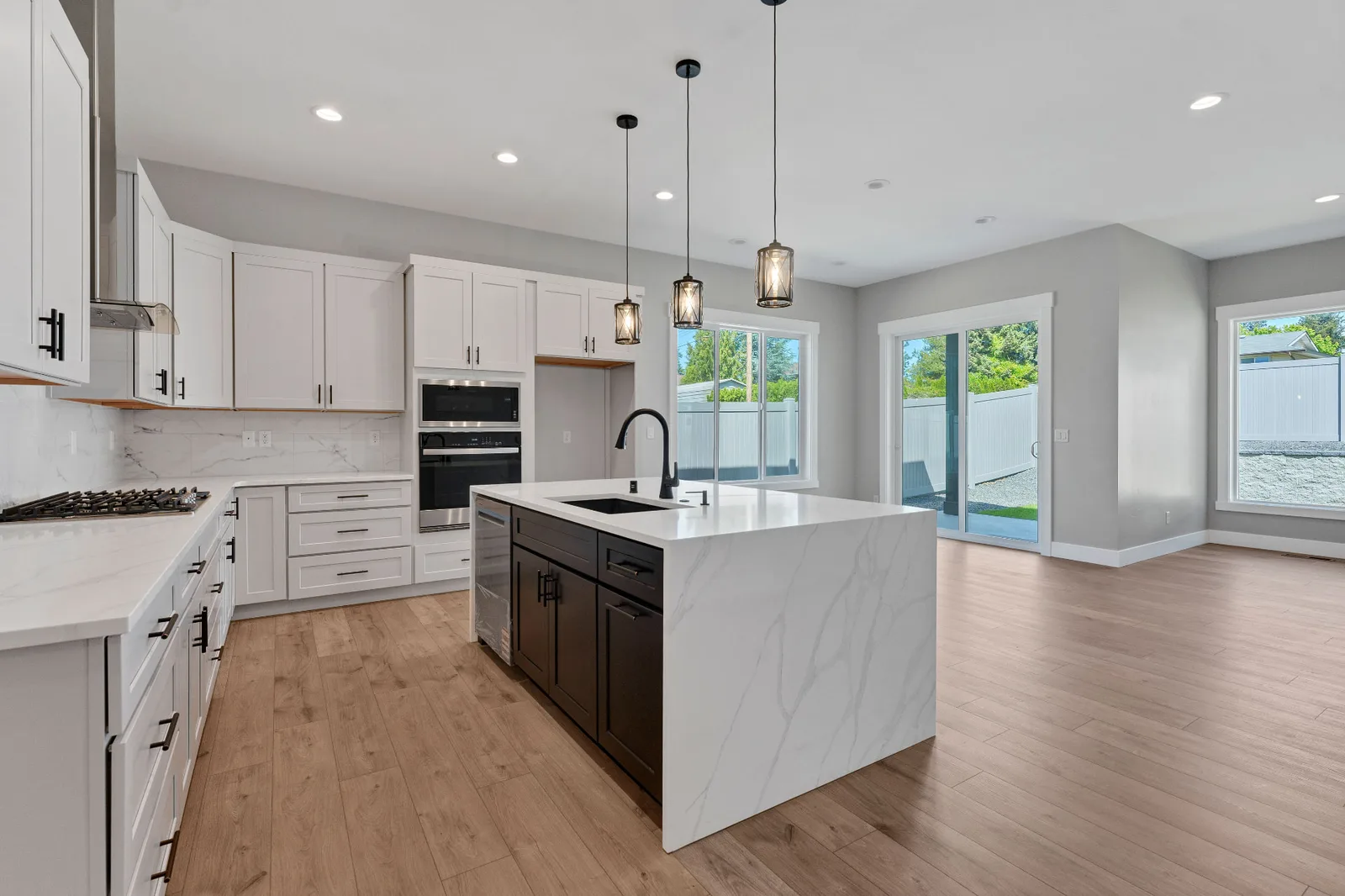 Open kitchen with quartz waterfall island, white cabinetry and dining area beyond