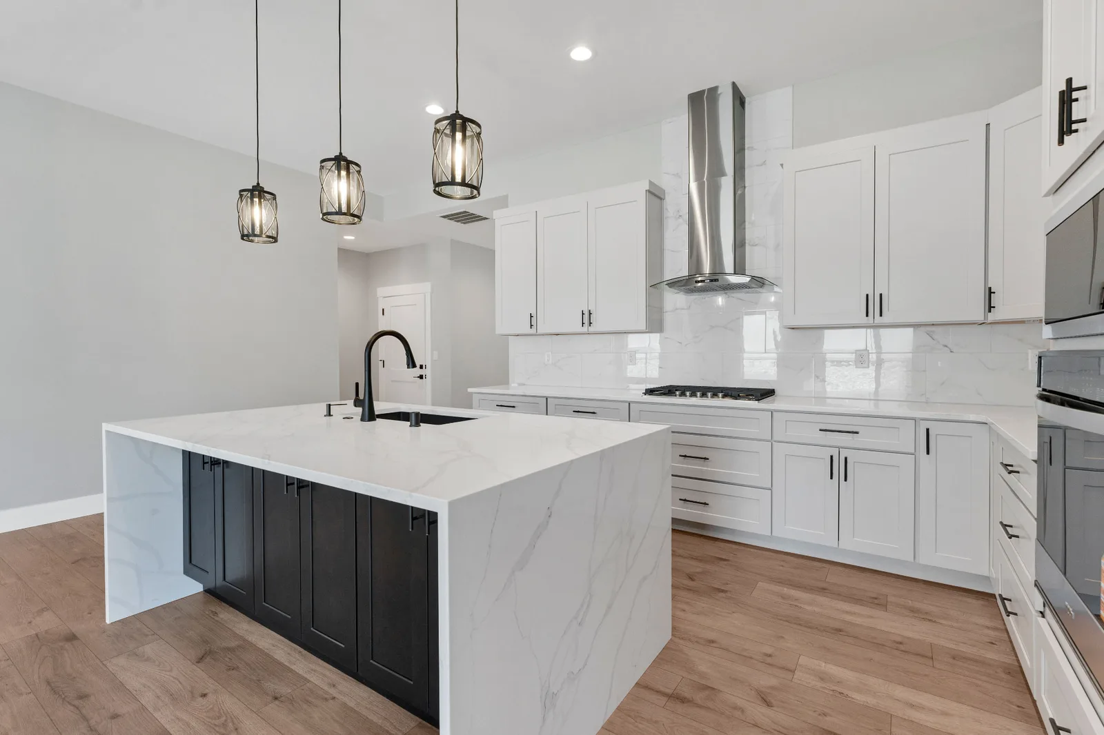 Kitchen range wall with stainless hood, marble-look backsplash and double ovens