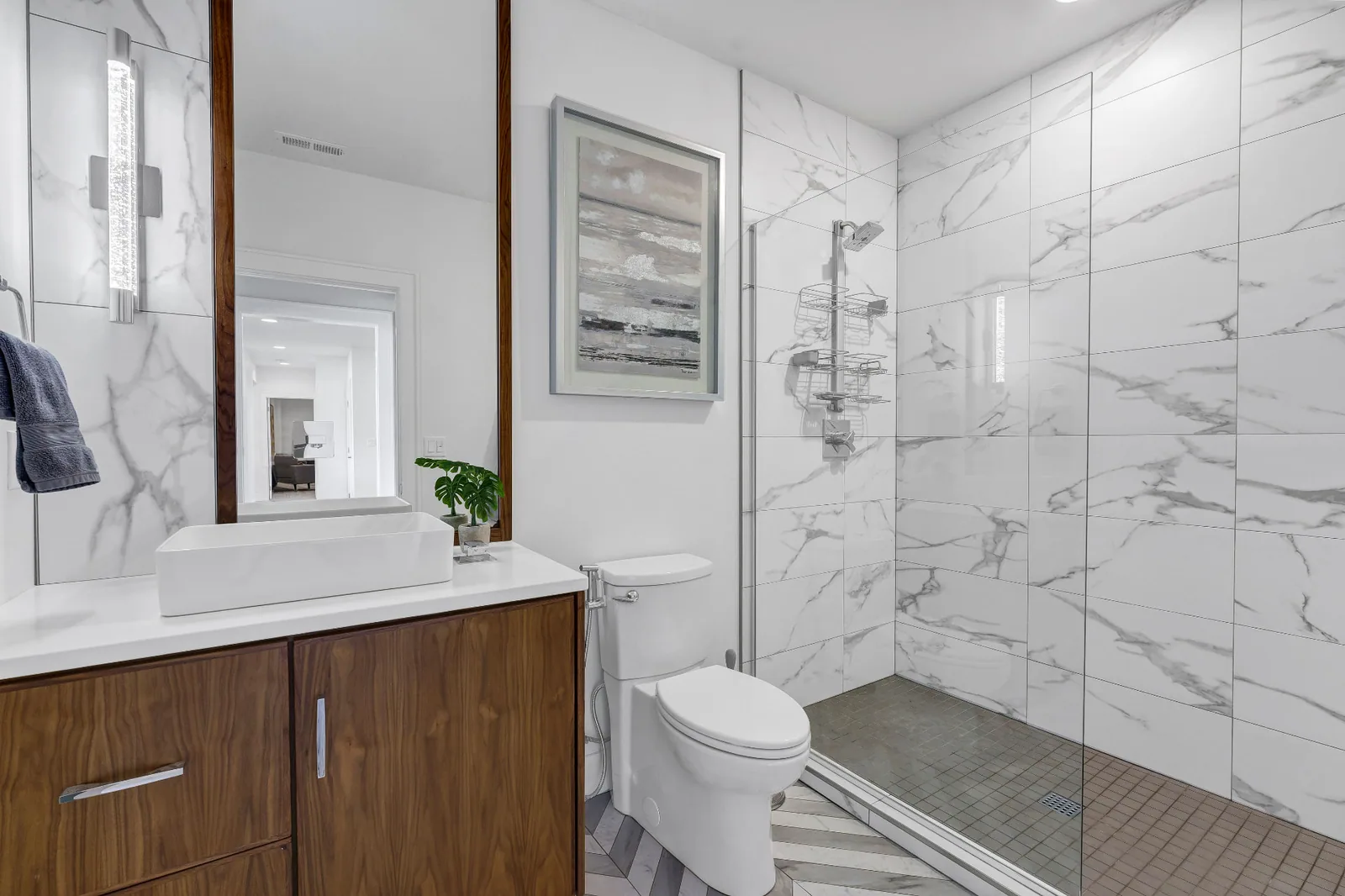 Guest bath with marble-look tile, walnut vanity and glass shower