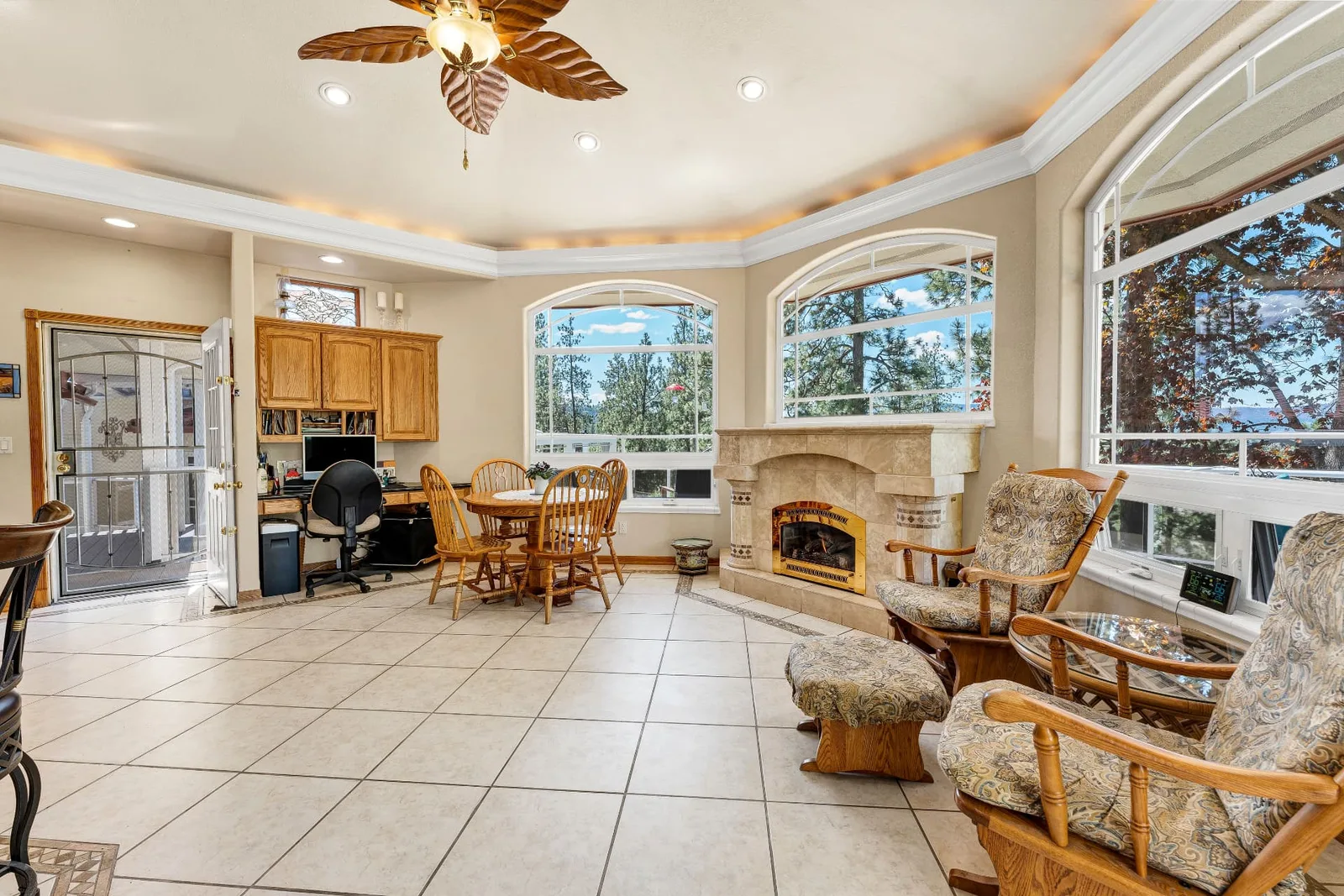 Family room with curved tray ceiling, stone fireplace, built-in desk and arched windows to the trees