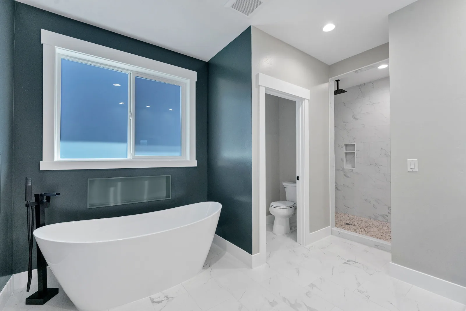 Primary bath with freestanding soaking tub, deep teal walls and tiled walk-in shower