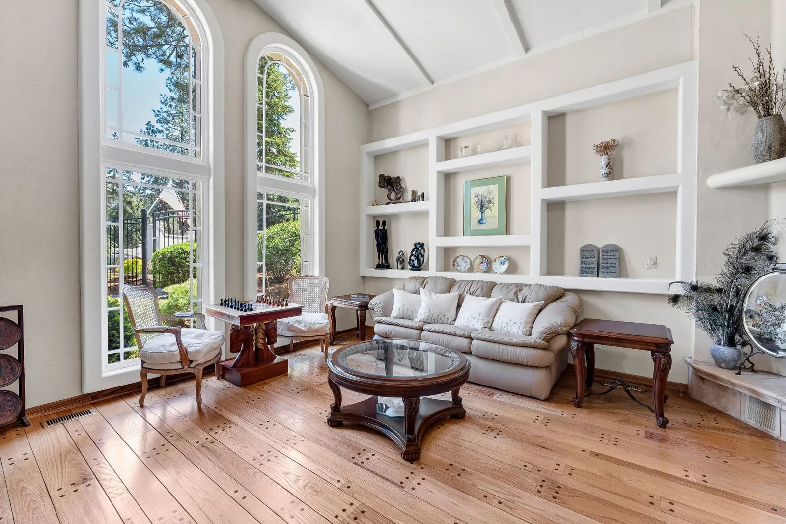 Formal living room with two-story arched windows and hardwood floors with inlay detail