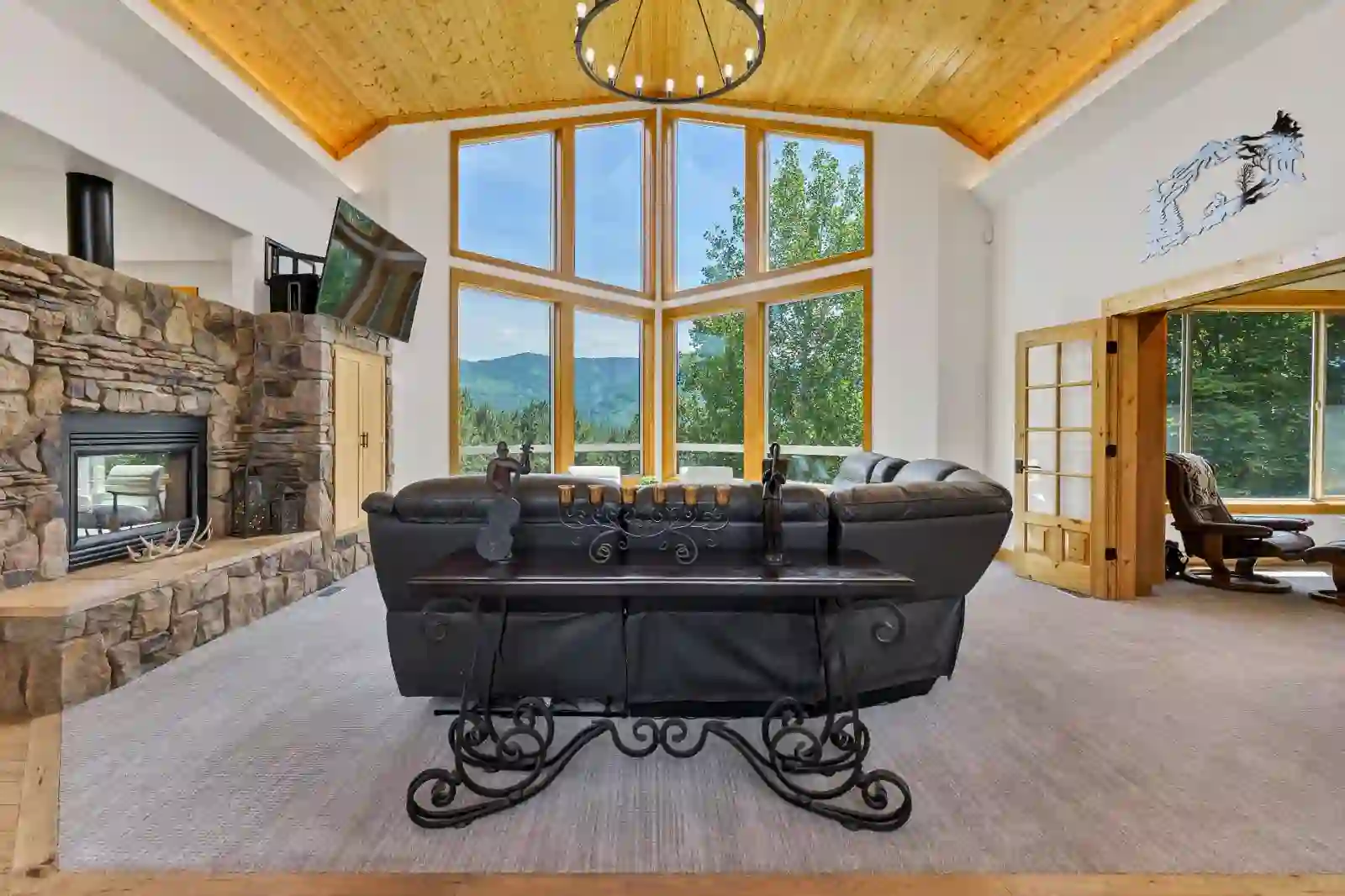 Second angle of the great room showing the floor-to-ceiling stone fireplace and mountain views