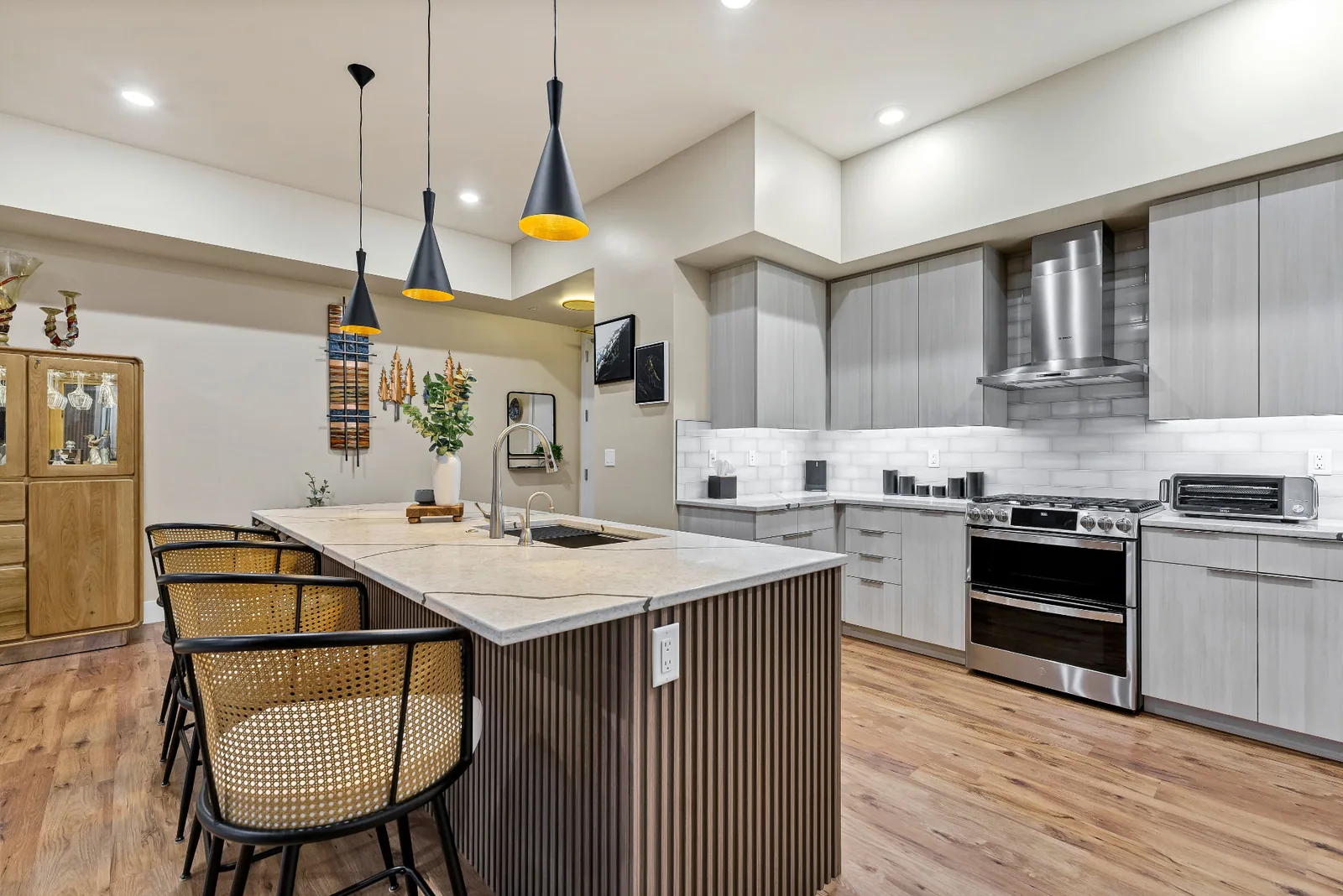 Kitchen with grey cabinetry, gas range and fluted island seating