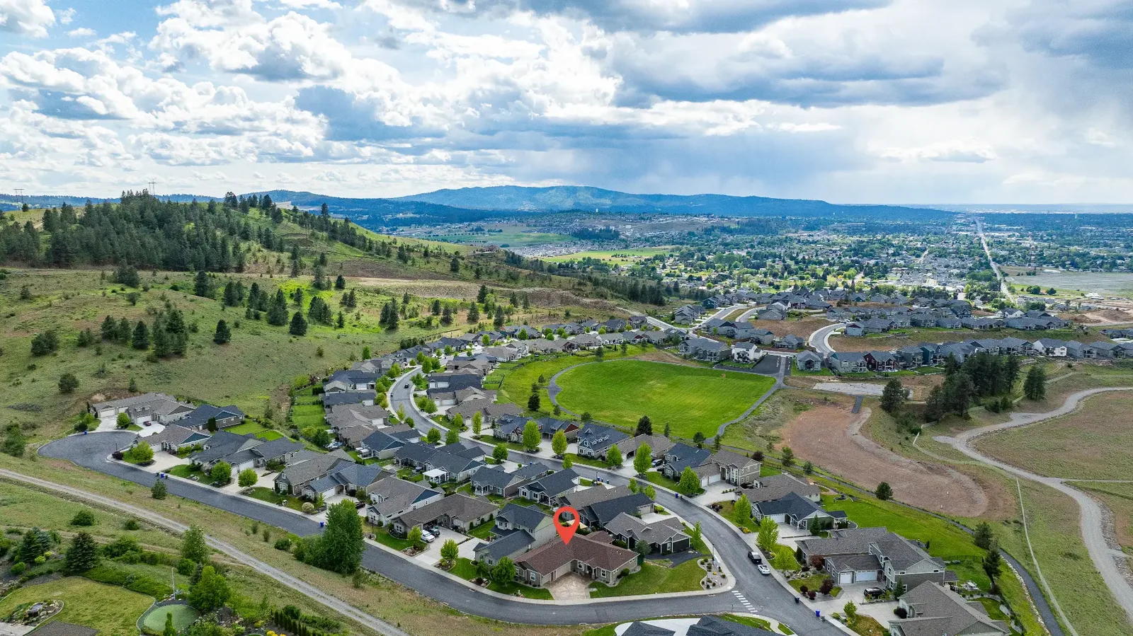 Aerial view of the home within its hillside neighborhood, valley beyond