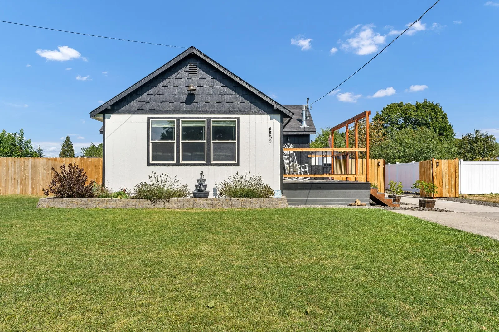 Side elevation with fenced lawn, landscaped beds and the cedar pergola deck