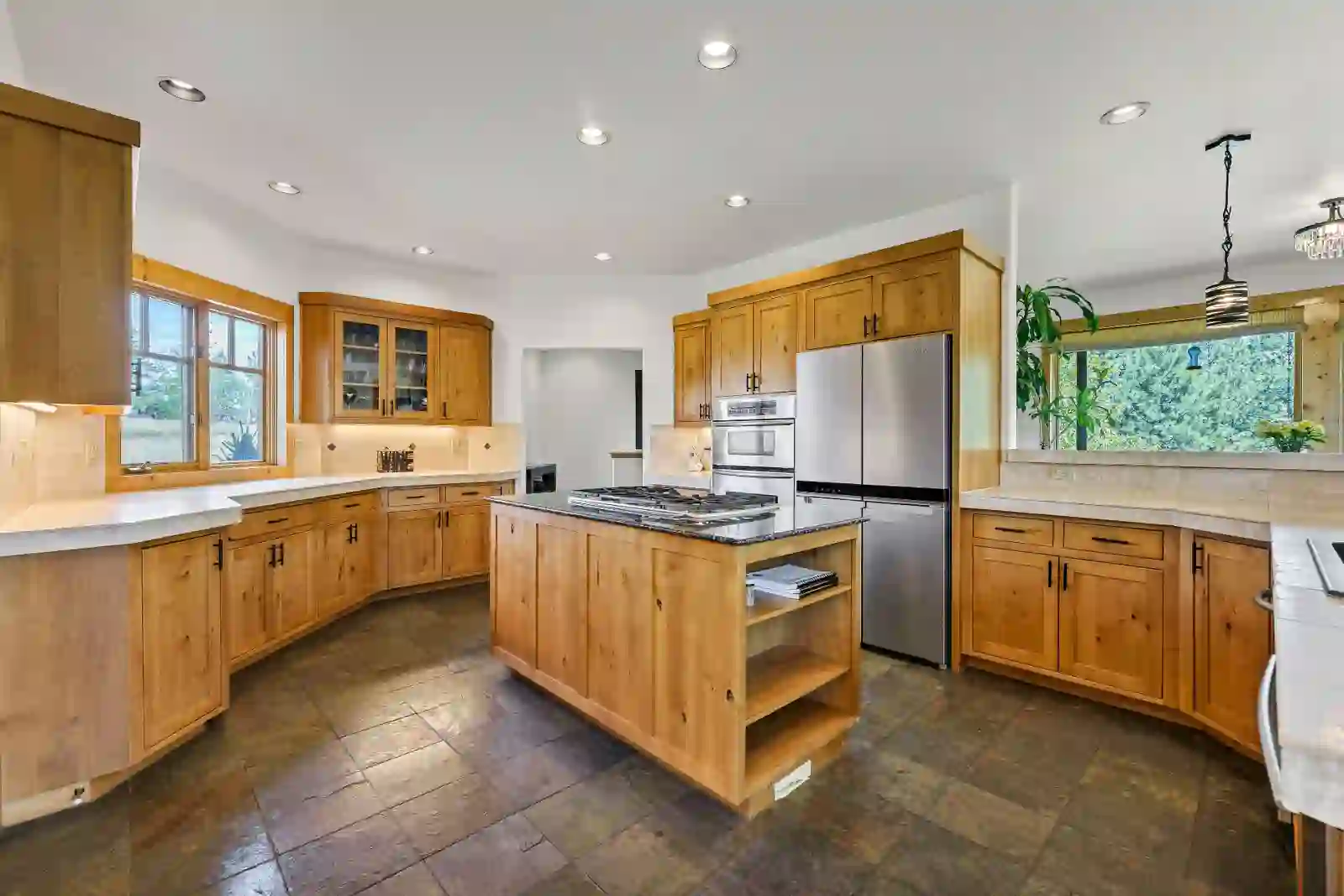 Kitchen with alder cabinetry, granite-topped island with gas cooktop and slate tile floors