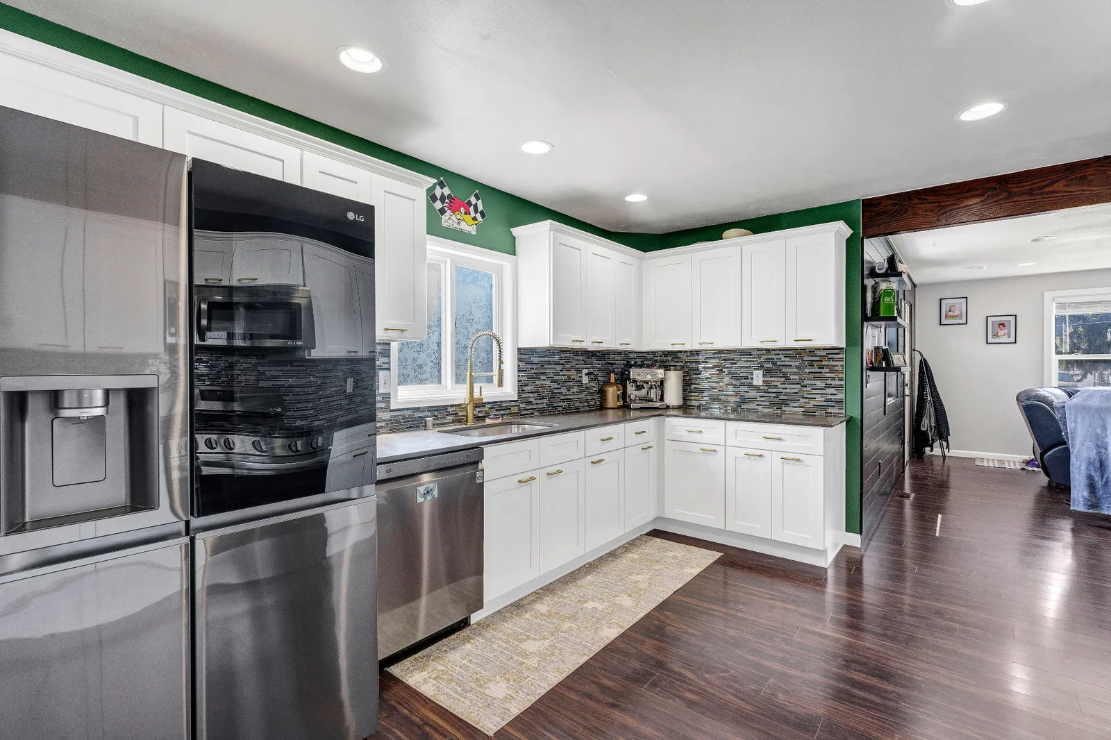Kitchen corner with stainless appliances, brass fixtures and green accent walls