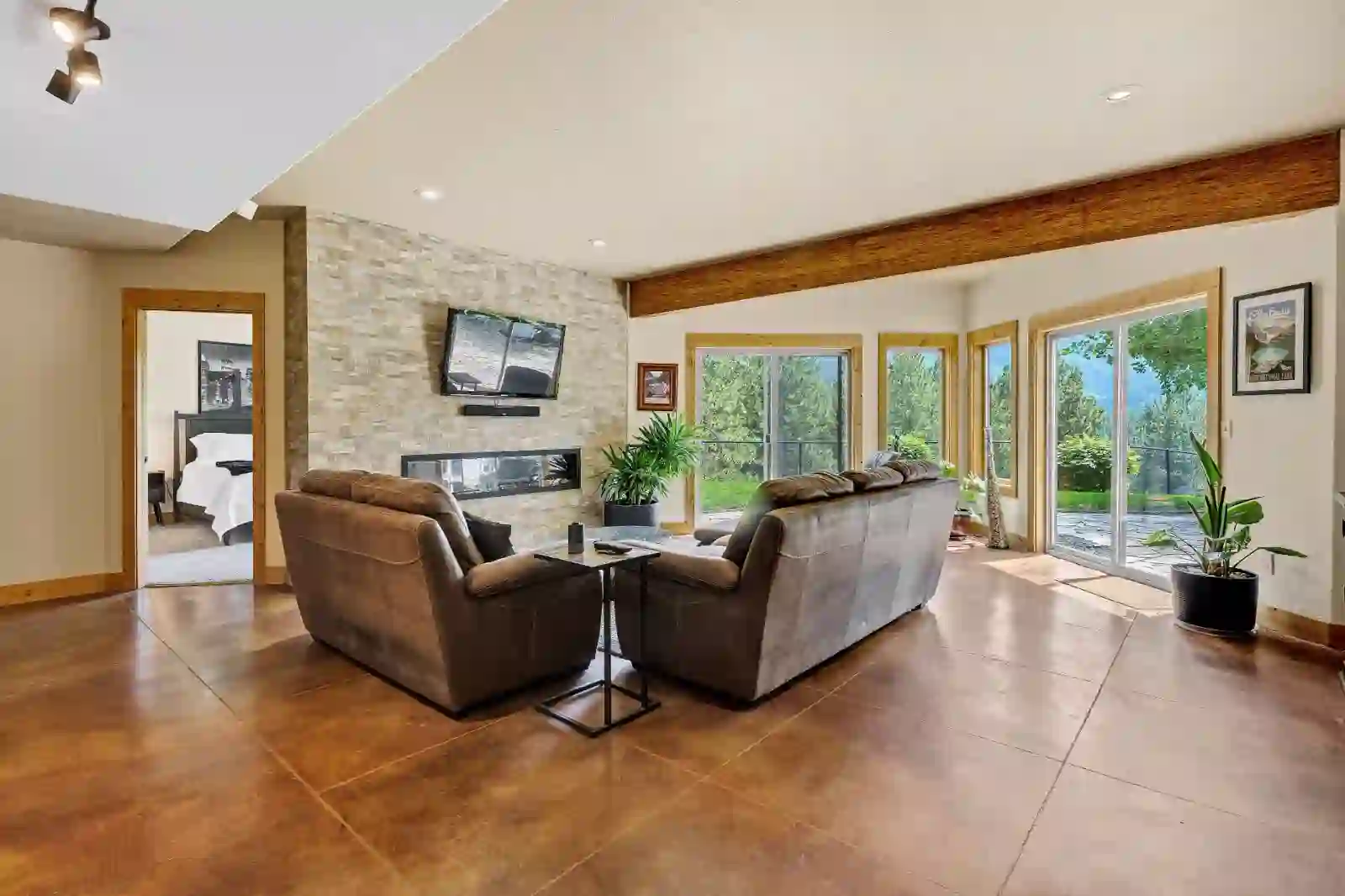 Lower-level family room with stone accent wall, linear fireplace and stained concrete floors