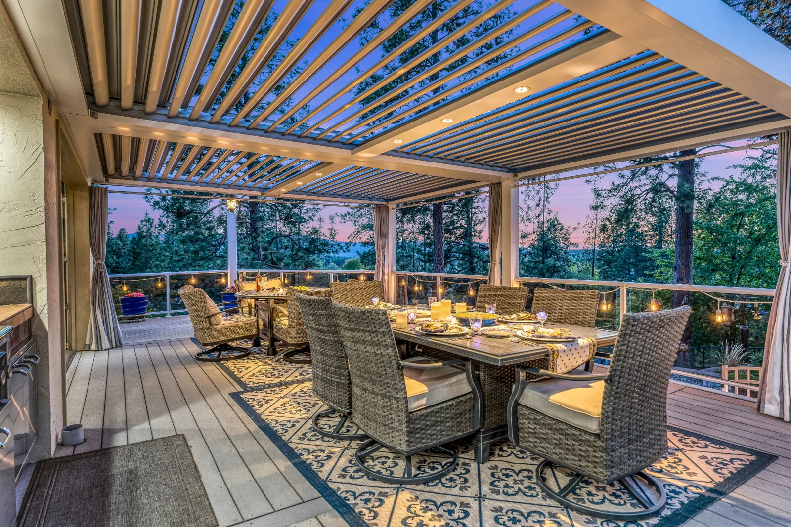 Louvered pergola dining deck with string lights and a treetop sunset view