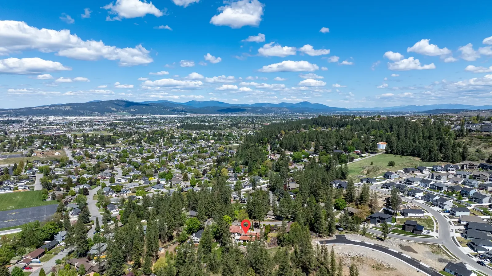 Aerial context view showing the property's hillside setting above the valley with mountain horizon