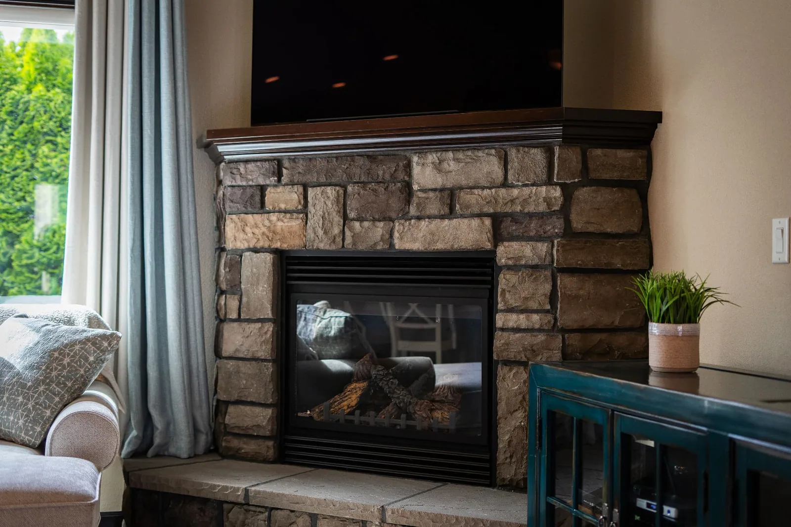 Stone gas fireplace with wood mantel in the living room