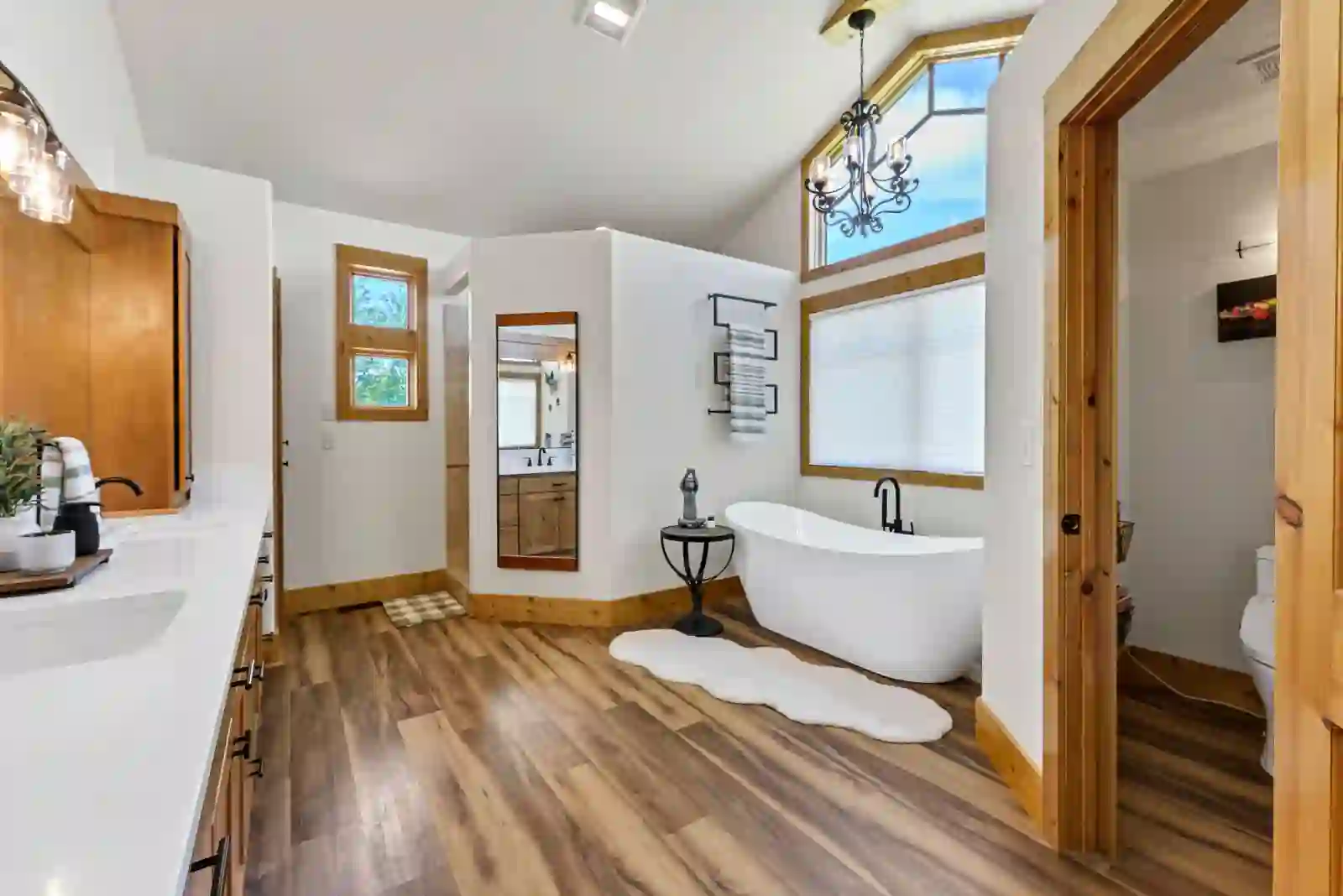 Primary bath with freestanding soaking tub beneath a vaulted ceiling and chandelier
