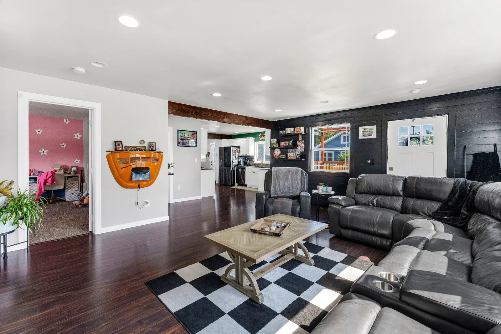 Open living room with dark hardwood floors, exposed wood beam and shiplap entry wall
