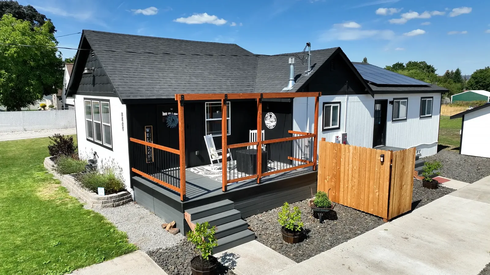 Elevated view of the black-and-white bungalow at 8809 E Cataldo with cedar pergola and covered front deck
