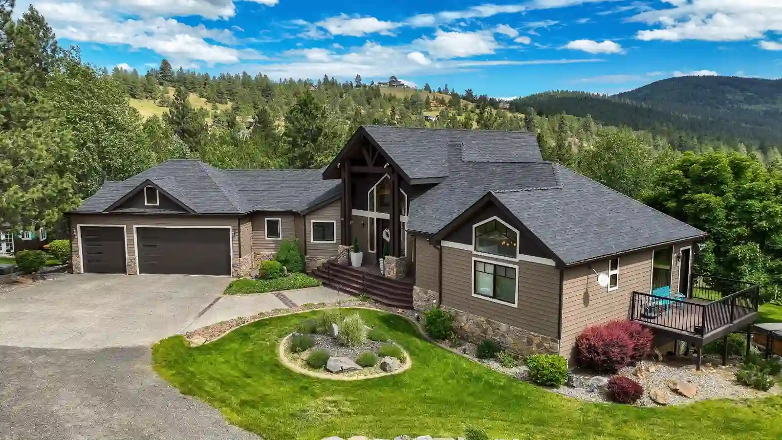Aerial view of the craftsman home at 23418 Broken Lance Ln set against forested hills