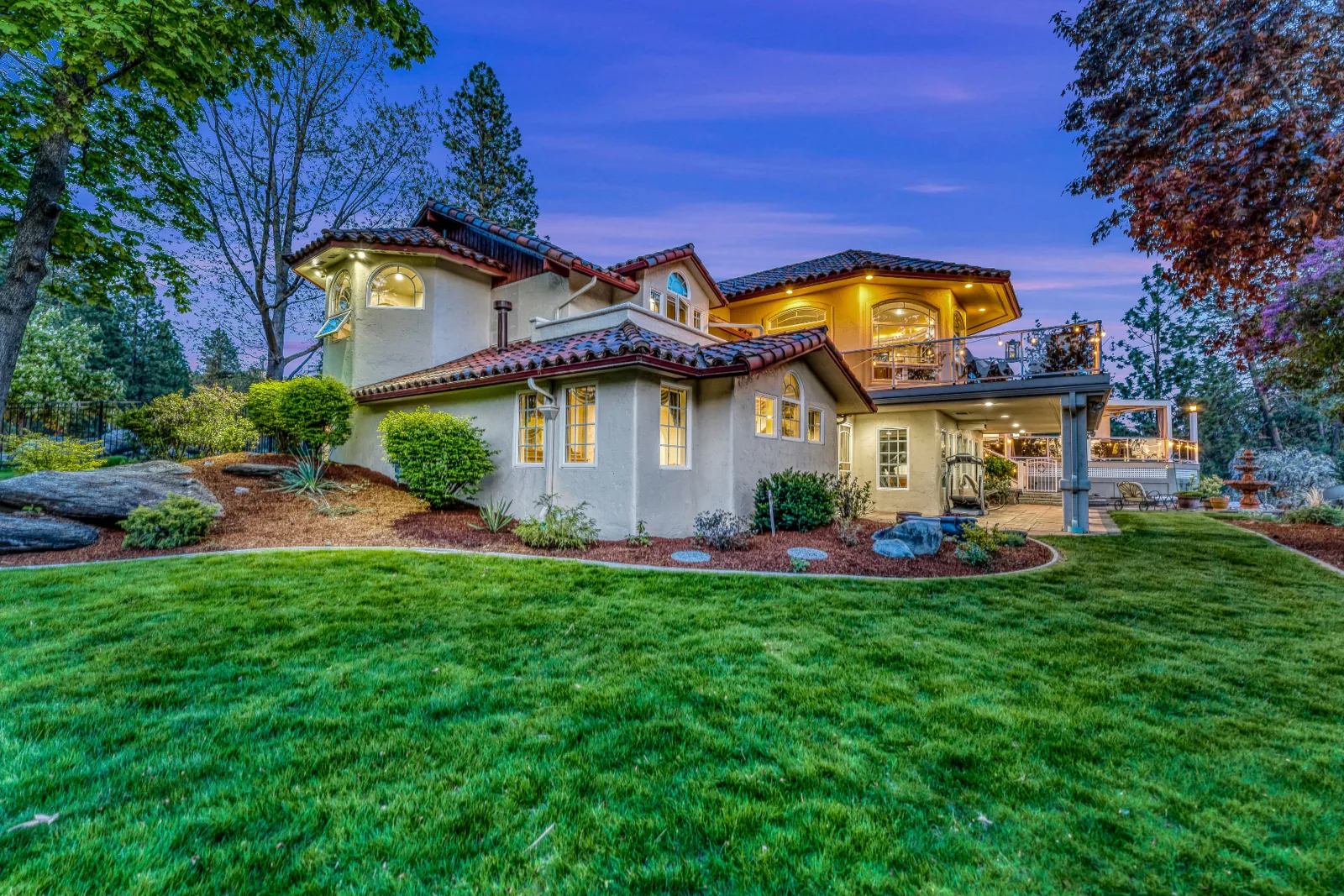 Twilight rear elevation of the Mediterranean estate over a manicured lawn