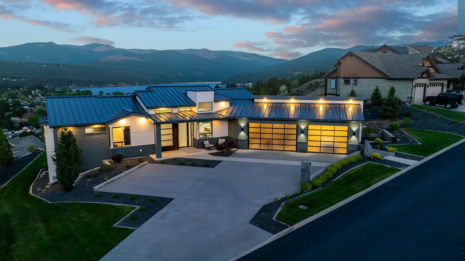 Twilight aerial of the modern hillside home above the lake at N Holiday Hills Dr