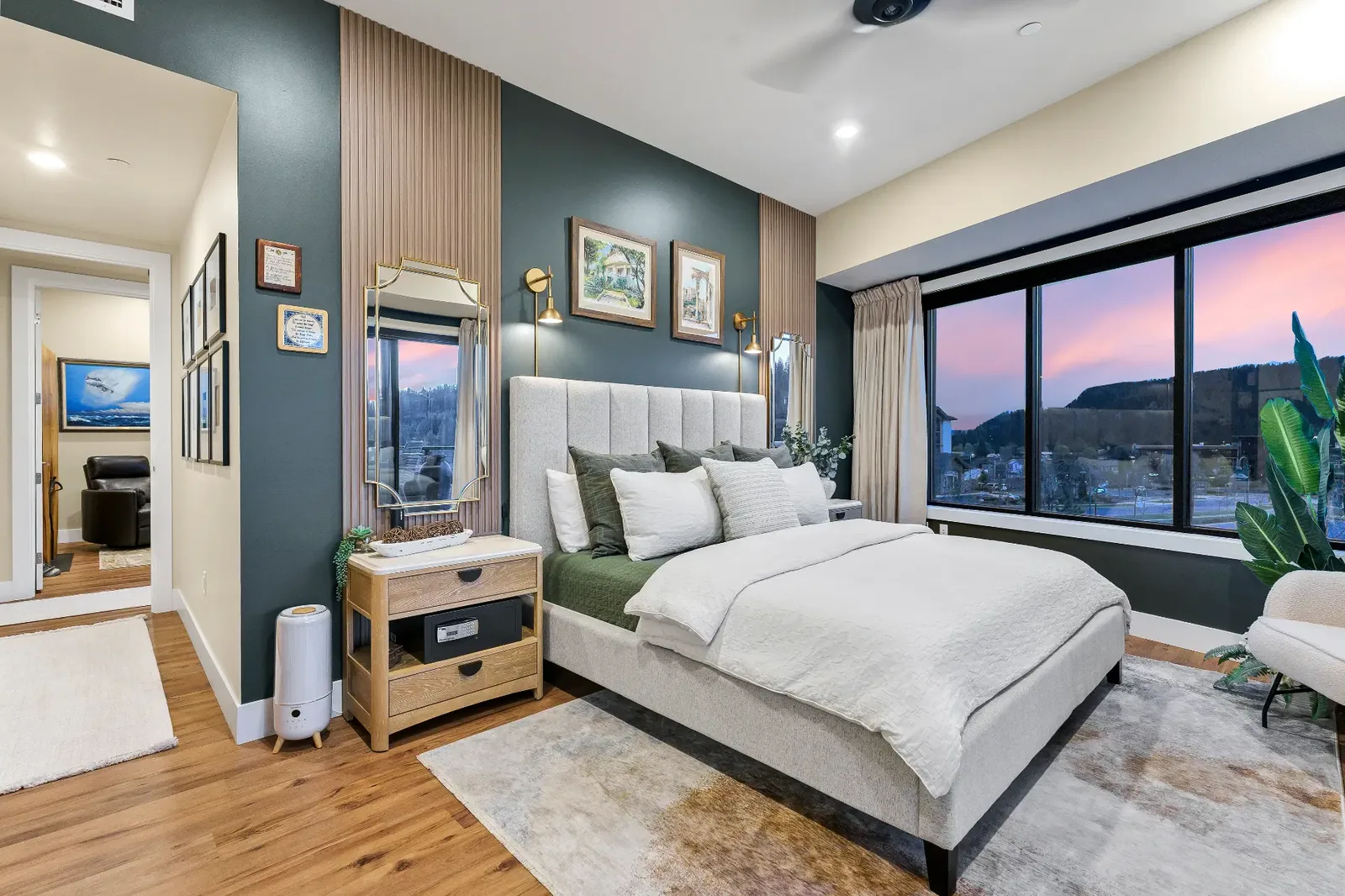 Guest bedroom with deep green accent wall and sunset view window