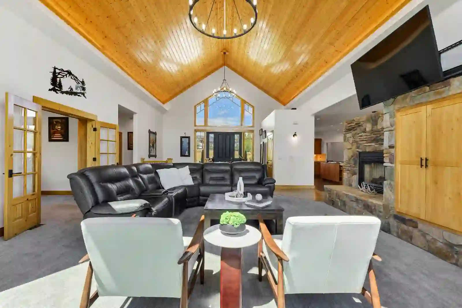 Great room with vaulted tongue-and-groove wood ceiling, stone fireplace and wall of windows