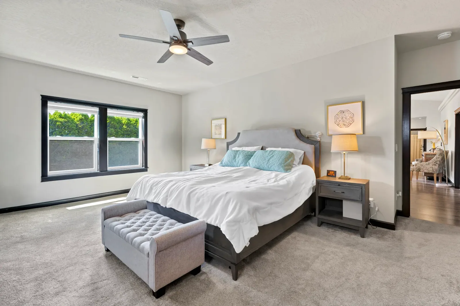 Primary bedroom with ceiling fan, carpet and window to the greenery