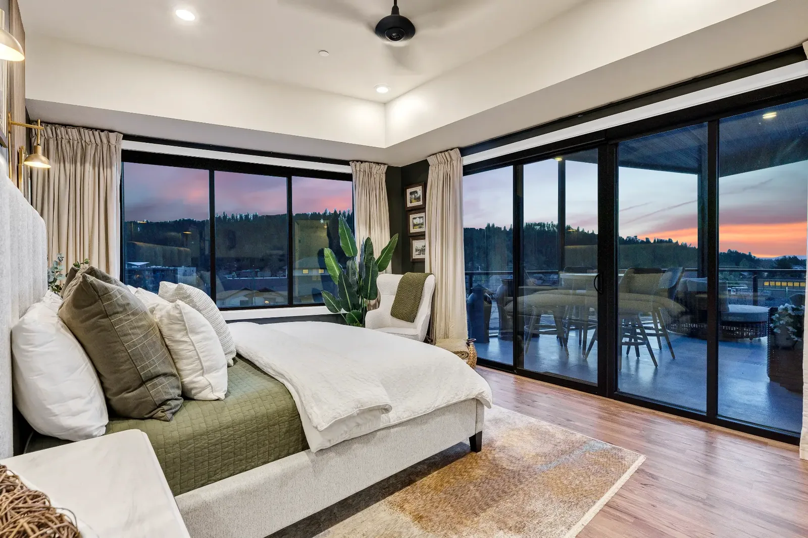 Primary bedroom with corner windows and sliding doors to the patio at twilight