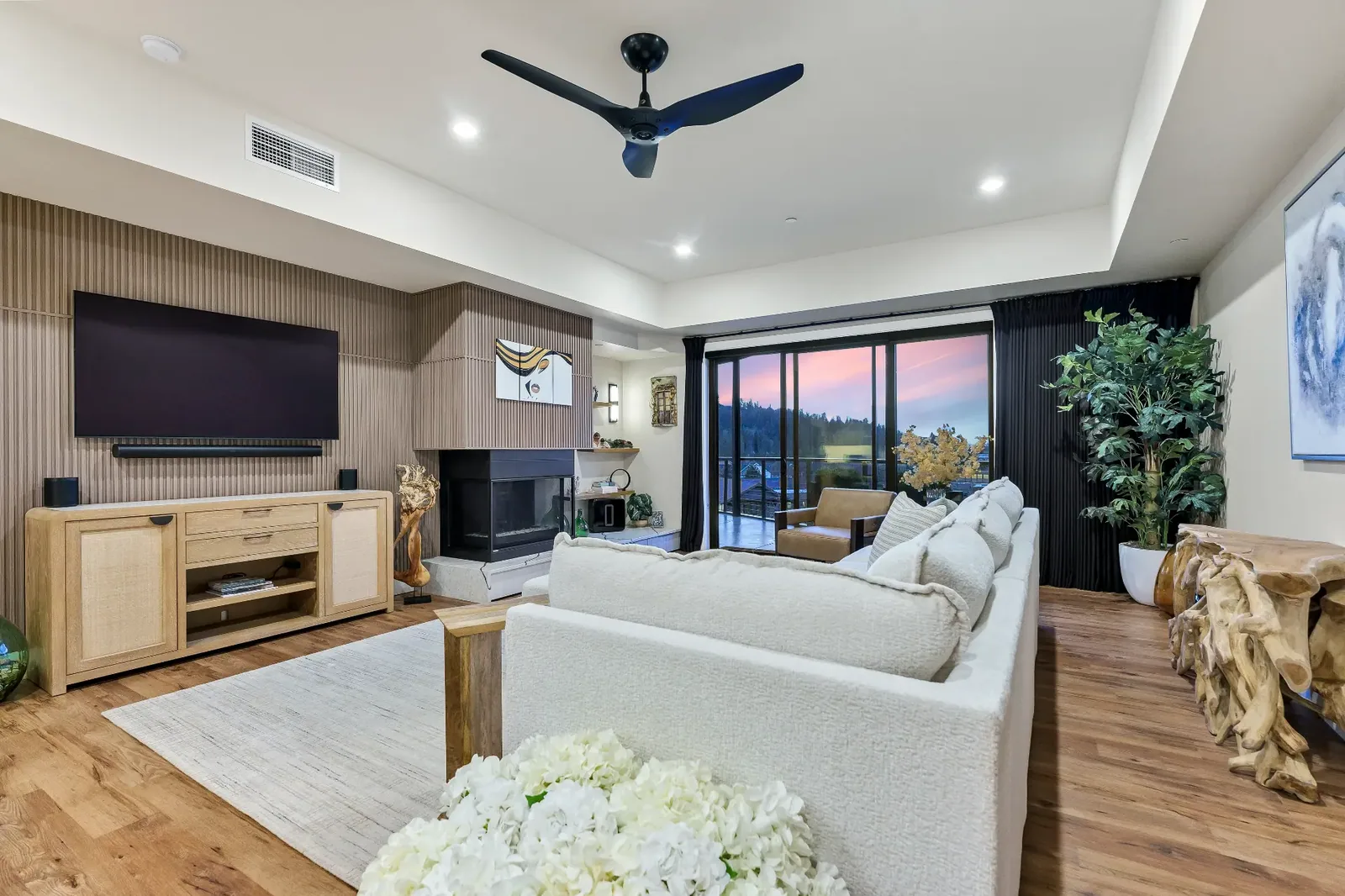 Living room with fluted wood wall, fireplace and twilight view through the sliding doors