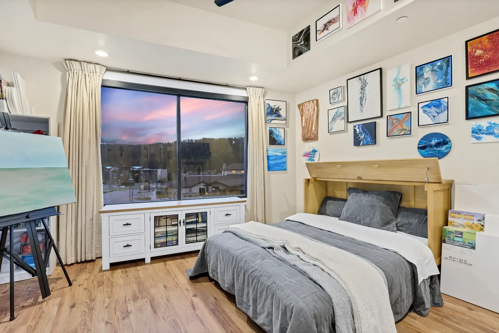 Bedroom used as an art studio with gallery wall and evening view
