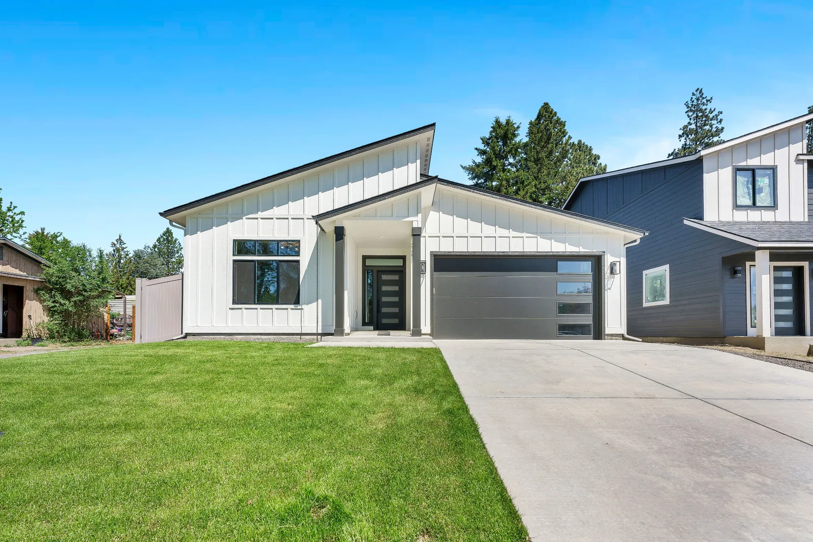 Modern front elevation with board-and-batten siding, dark entry door and two-car garage at 3137 E 36th