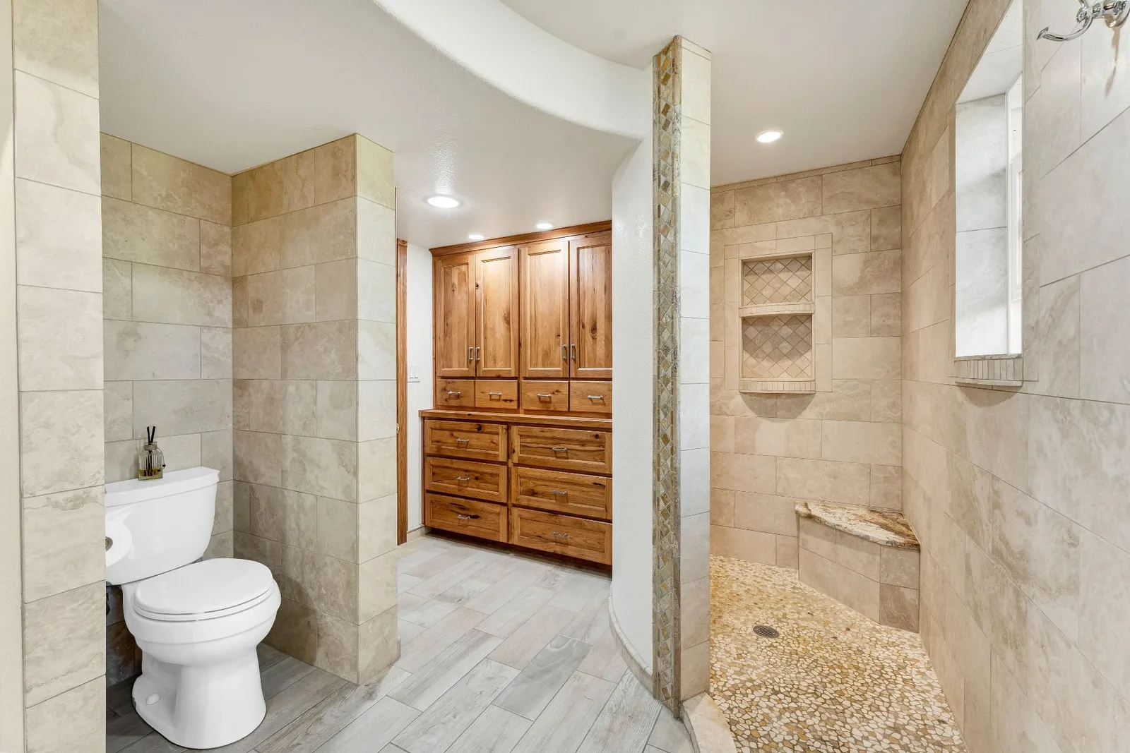 Bathroom with walk-in pebble-floor tile shower and built-in hickory cabinetry