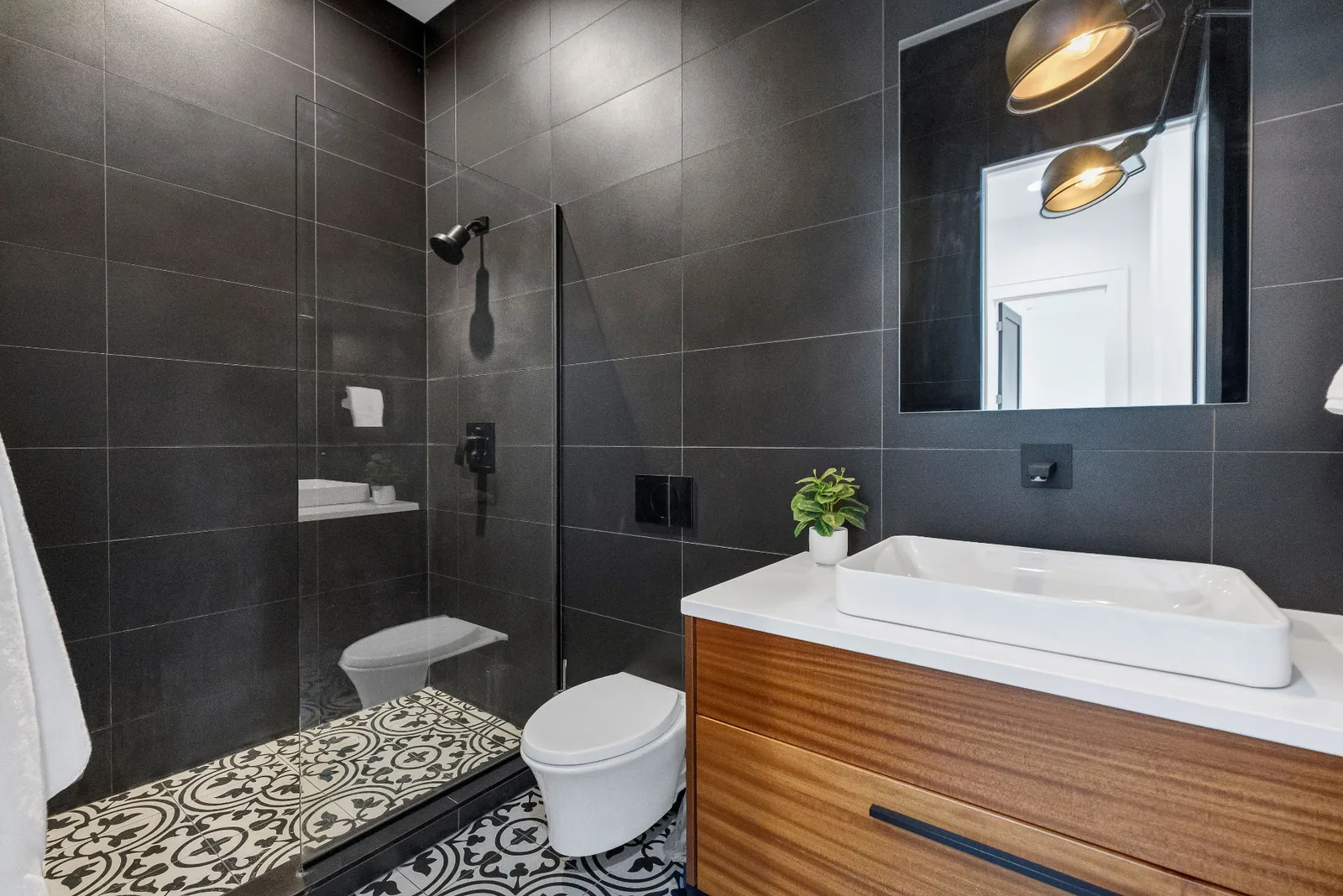 Second bath with charcoal tile, patterned floor and floating wood vanity