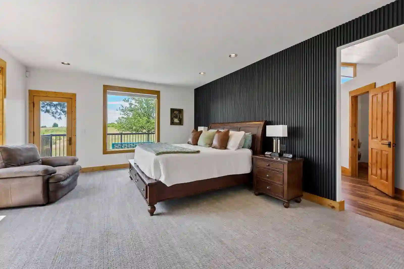 Primary bedroom with black slat accent wall and private deck access