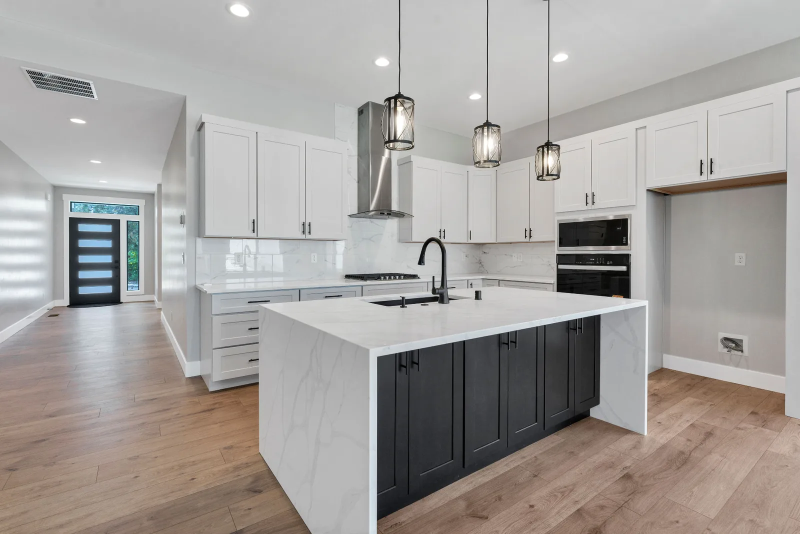 Kitchen island and pendant lighting with the front entry in the background
