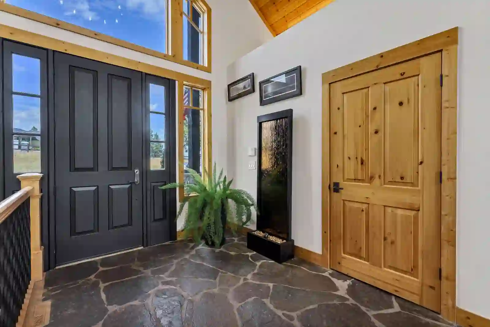 Entry foyer with flagstone floor, black front door and alder trim beneath clerestory windows